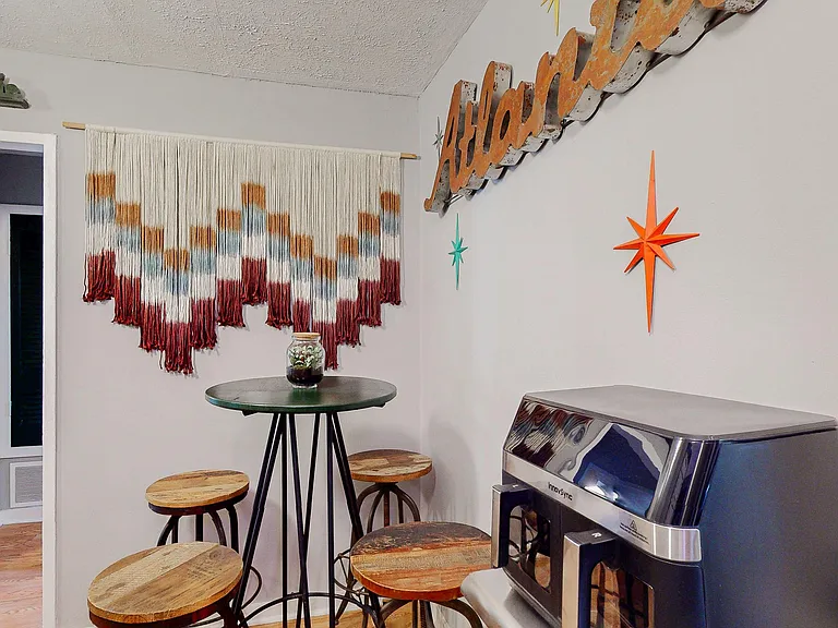 Compact dining nook with a high-top table, four stools, and tasteful wall decorideal for quick meals or coffee breaks.
