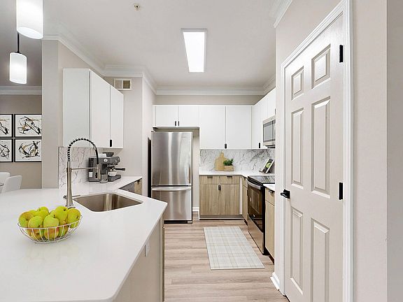Bright kitchen with two toned cabinets with breakfast bar and view of dining room