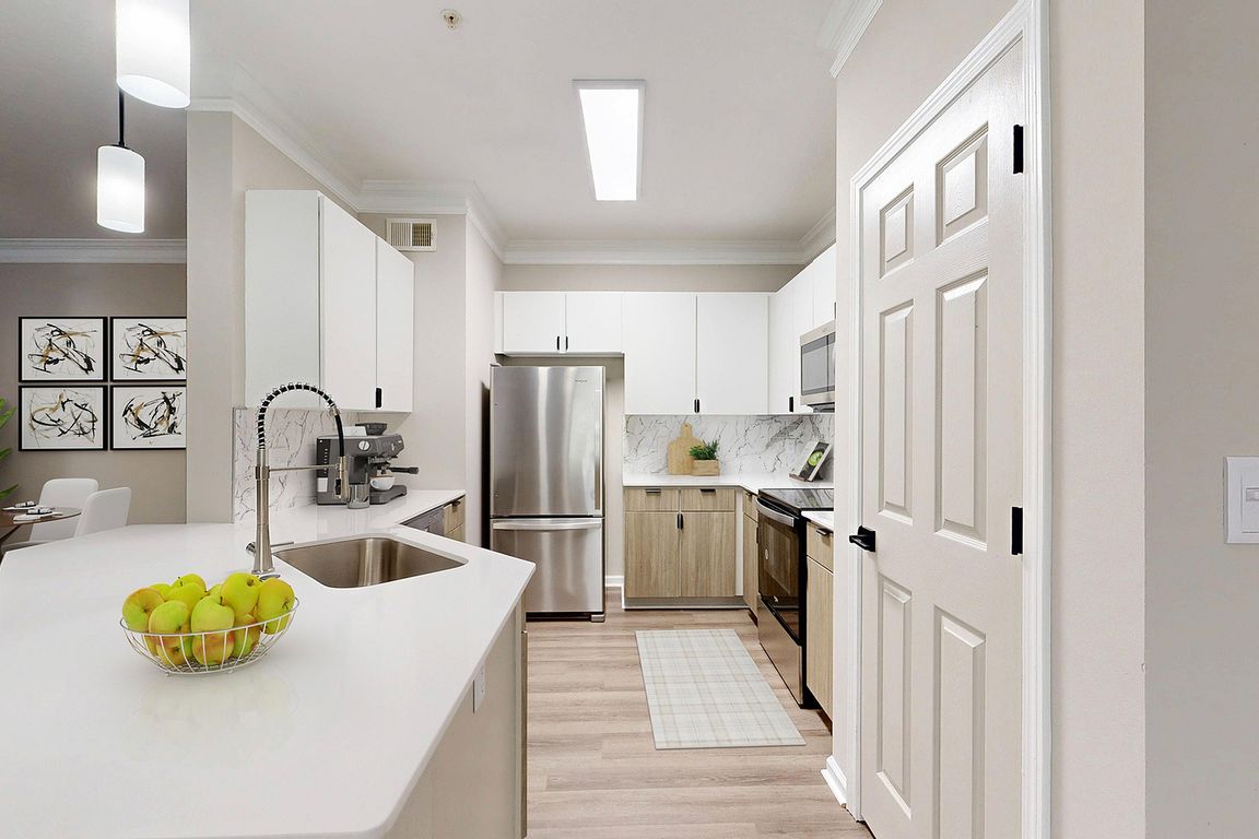 Bright kitchen with two toned cabinets with breakfast bar and view of dining room