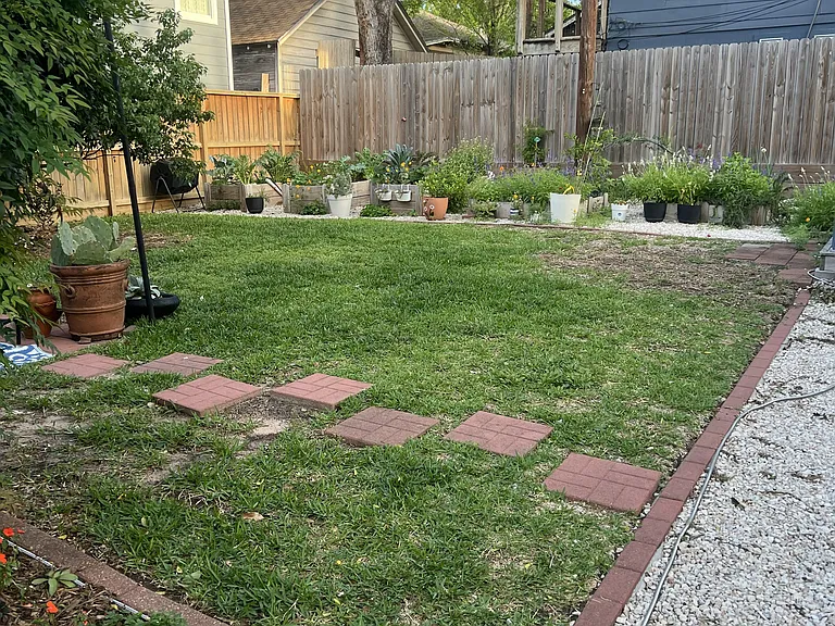 Manicured backyard with vegetable and herb garden and flower beds throughout