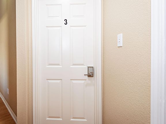 Interior hallway with hardwood-style flooring and a private room entry featuring a secure keypad lock for access control.