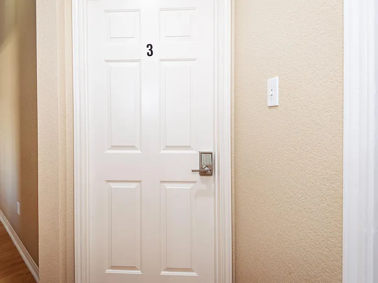 Interior hallway with hardwood-style flooring and a private room entry featuring a secure keypad lock for access control.