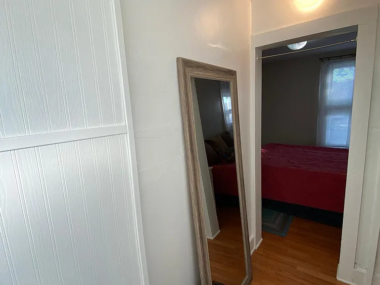 The high closet ceiling, bench, and white walls open to the Third bedroom. The closet is visible unless closed by curtains.