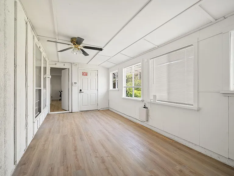 Flexible bonus room with durable wood-look flooring, ceiling fan, and multiple windows with blinds for light and privacy.
