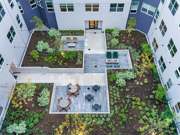 Unwind in the lushly landscaped courtyards at Modera Woodstock, where cozy lounge seating and a fire table create the perfect outdoor retreat in the heart of Portland.