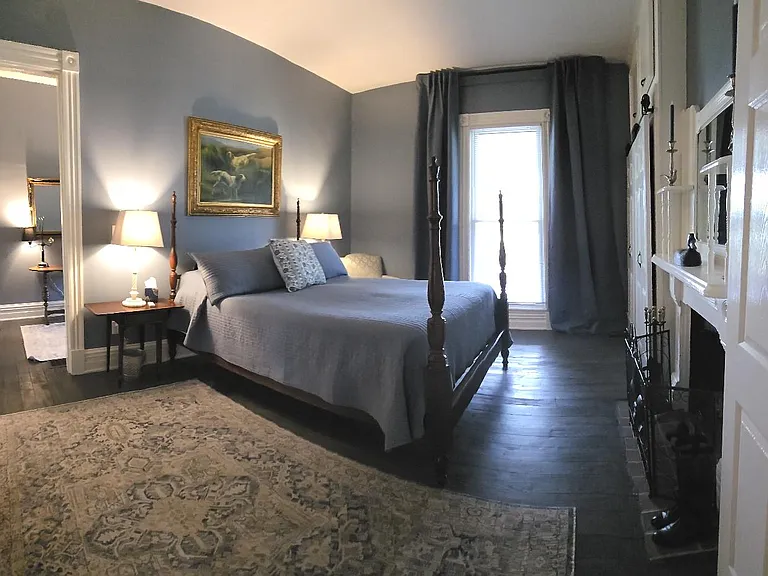 Panoramic view of primary BR with Spring/summer decor. Queen sized four poster bed. Black out curtains (light, sound). Ceiling fan.