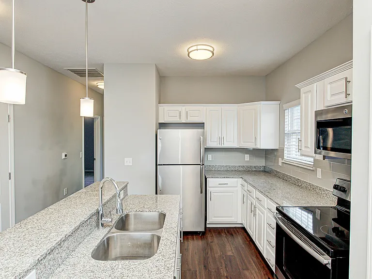 A sleek kitchen designed for everyday living_granite countertops, a glass-top stove, stainless steel appliances, and a kitchen island that doubles as a breakfast bar.