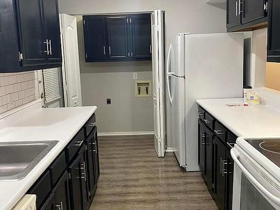 sleek black resurfaced cabinets with white subway tile backsplash, stainless steel contemporary faucet and cabinet pulls, grey vinyl plank flooring