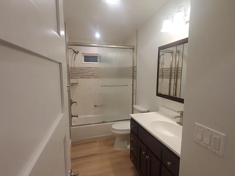 Bathroom #2 with new mirrored medicine cabinet, sink, vanity, lights, toilet, tub, shower tile and doors