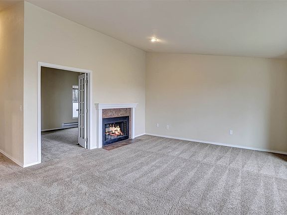 The living room offers the perfect ambiance with the natural light and the cozy fireplace.>