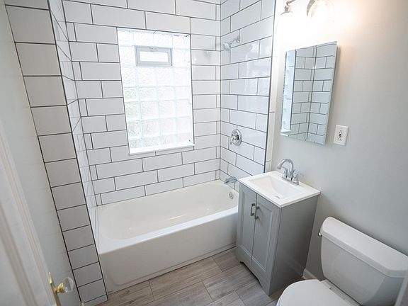 Bathroom is white and bright with ceramic tile floor and subway tiled shower and deep bathtub.