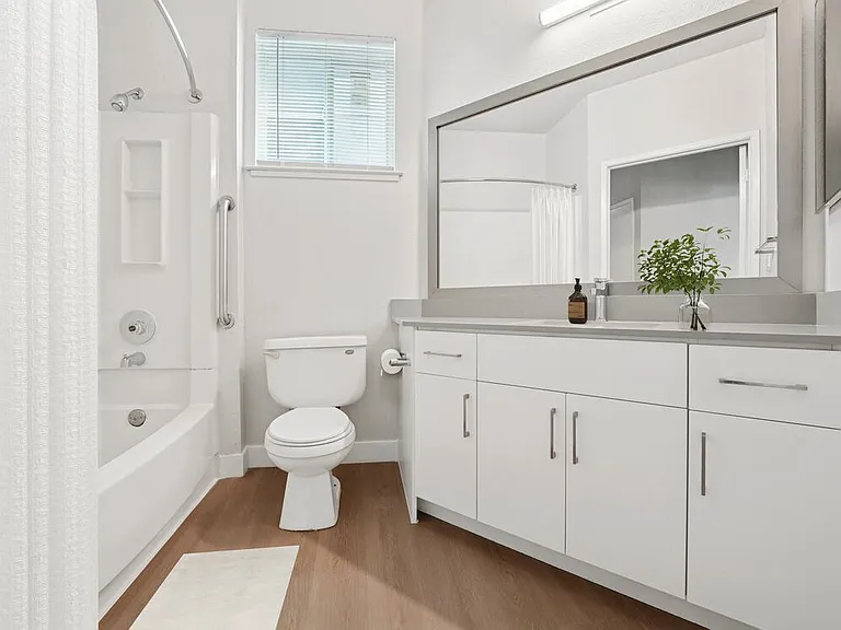 Renovated Package I bath with white cabinetry, grey quartz countertops, and hard surface flooring