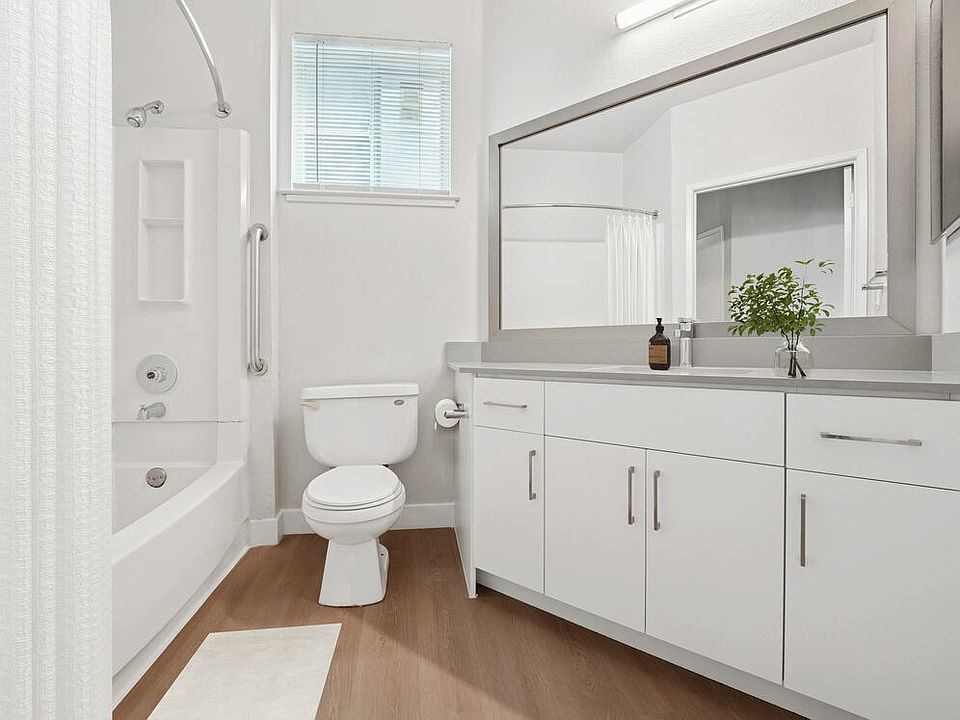 Renovated Package I bath with white cabinetry, grey quartz countertops, and hard surface flooring