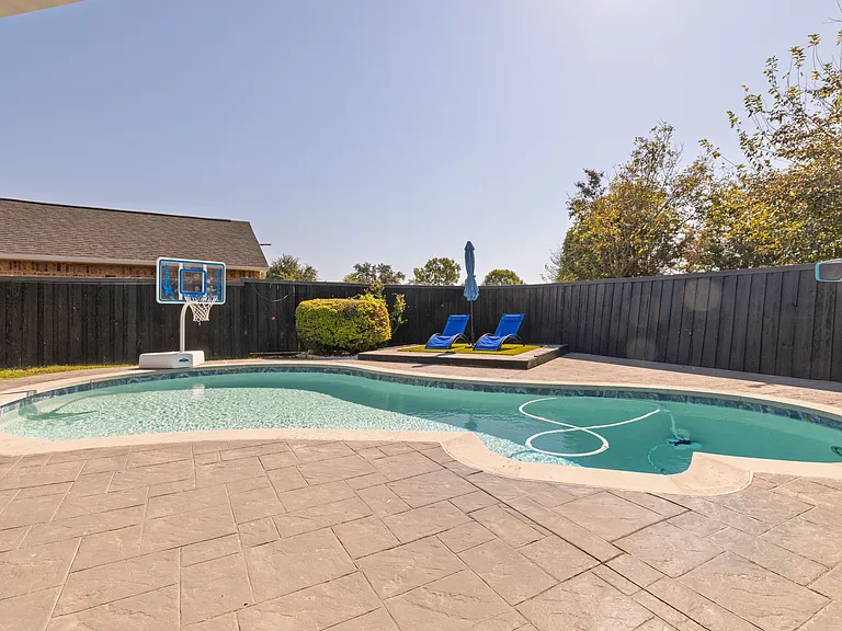 Go swimming in the pool with sun loungers, an umbrella, a floaters rack, pool lights, a basketball hoop as well as a beautiful view of the property in this fully-fenced yard.