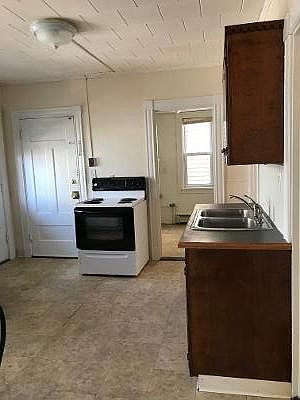 White door on left is entrance to appartment into kitchen, door to the right of stove leads to pantry