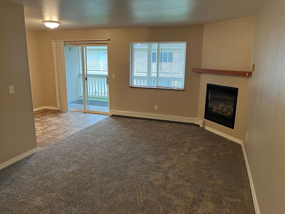 Living room featuring carpet, electric fireplace, mantle, and sliding glass door to balcony and exterior storage closet.