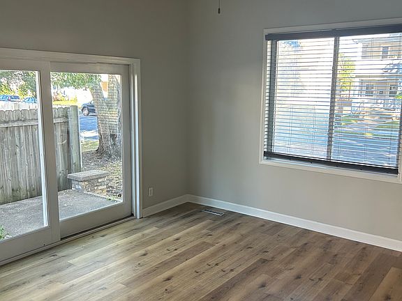 Living room with new floors, sliding glass door, large picture window, and ceiling fan.