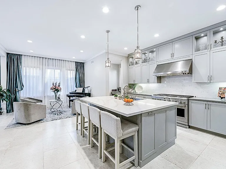 Custom beautiful gray cabinets. beautiful polished nickel pendants. Quartz counters with a custom marble backsplash.