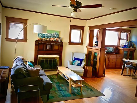 Living room with fireplace and oak floors as viewed from office/study with French doors. To right is dining room with built-in Mission Style quarter sawn oak cabinets.