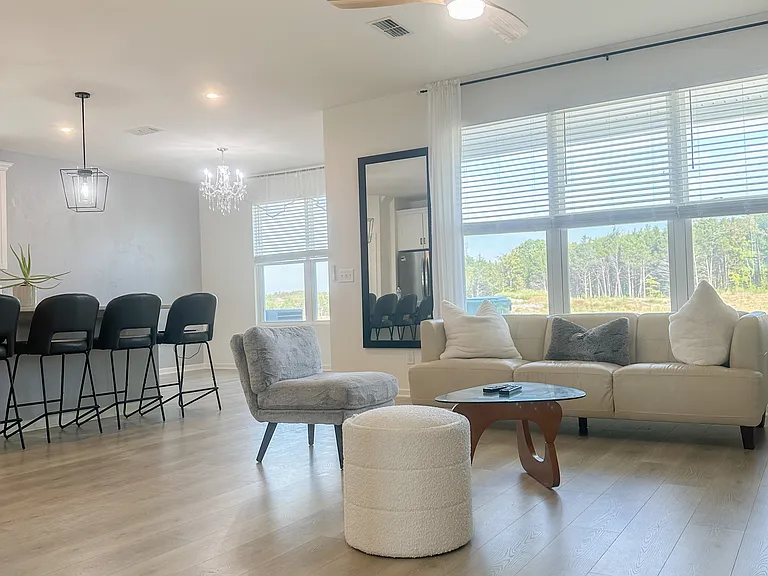Open-concept living, dining, and kitchen areas with views of serene wooded backyard designed for natural light, relaxation and effortless entertaining.
