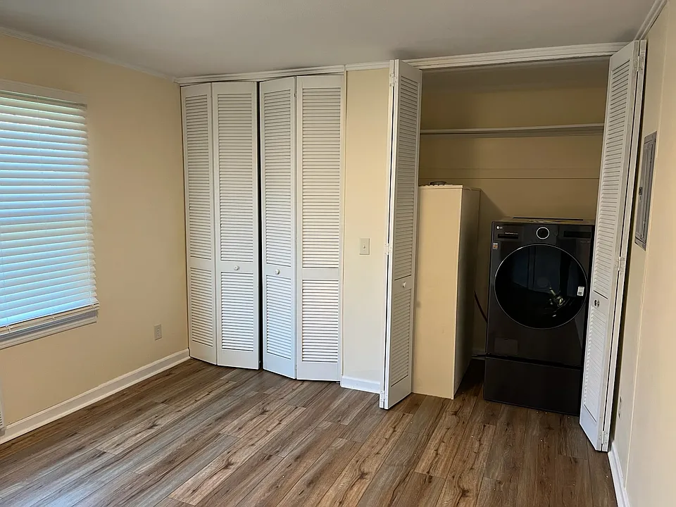 A walk-in closet with a combination washer and dryer in the bedroom.