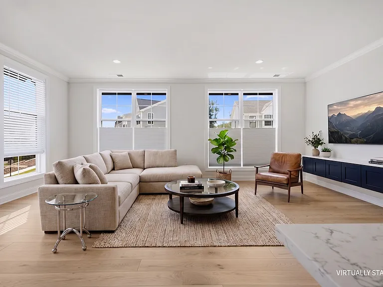 Airy, spacious living room features gorgeous natural light, custom built-in cabinetry, and storage closet.