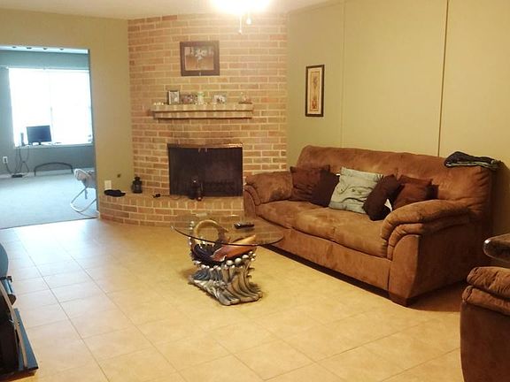 SPACIOUS FAMILY ROOM WITH A FIREPLACE AND TILE FLOORS THAT OVERLOOKS KID'S PLAYROOM, KITCHEN, AND BEDROOMS.