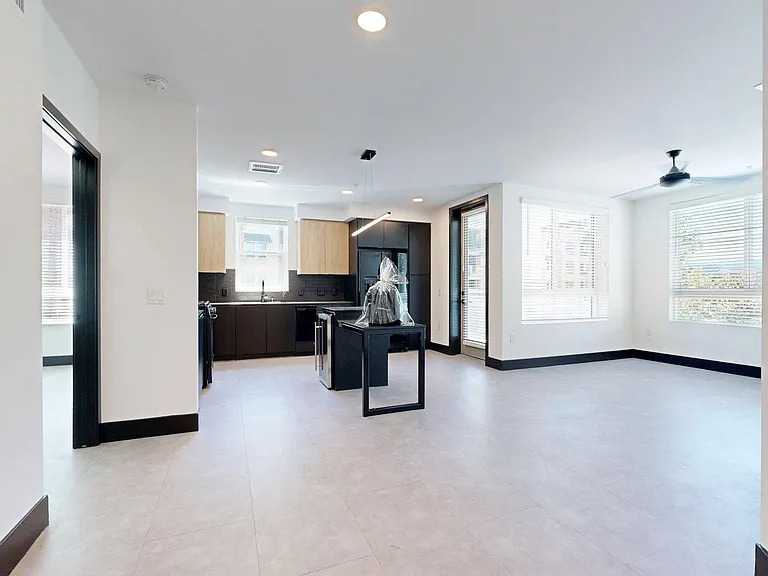 Apartment Kitchen with Stainless Steel Appliances, Dining and Living Room with Wood-Style Flooring.