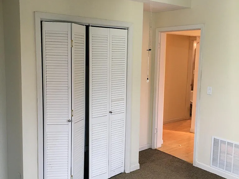 View #3 of bedroom looking out into living room and HVAC closet behind bifold doors