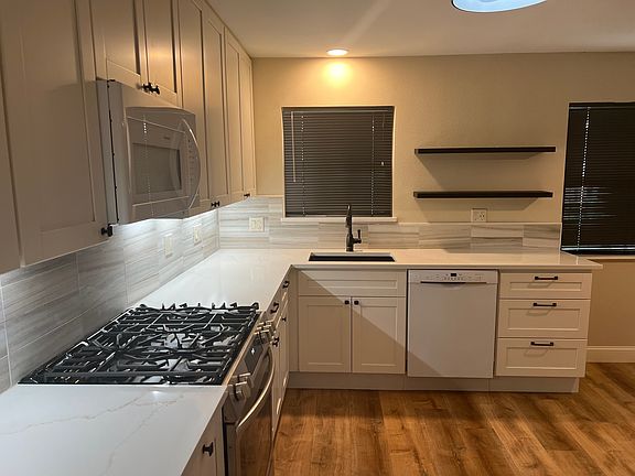 Plenty of counter space in this kitchen, with under-counter lighting to make food prep easier. Dishwasher and disposal make cleanup quicker. And a full set of drawers next to the dishwasher for flatware and all those smaller items. Open shelving too!