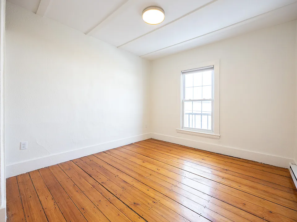Bright bedroom with hardwood floors and large window
