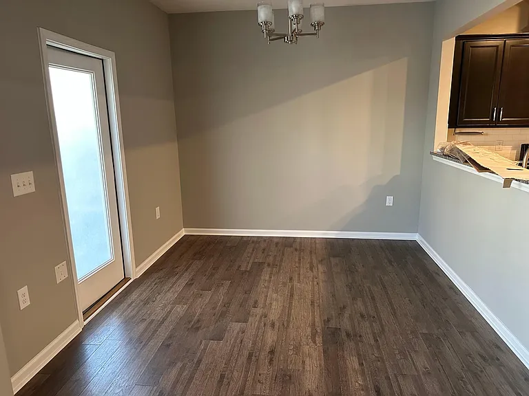 A view of the dining area where you can see the exterior patio door and the pass through to the kitchen.