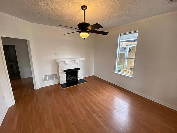 Den with ceiling fan and decorative fireplace.