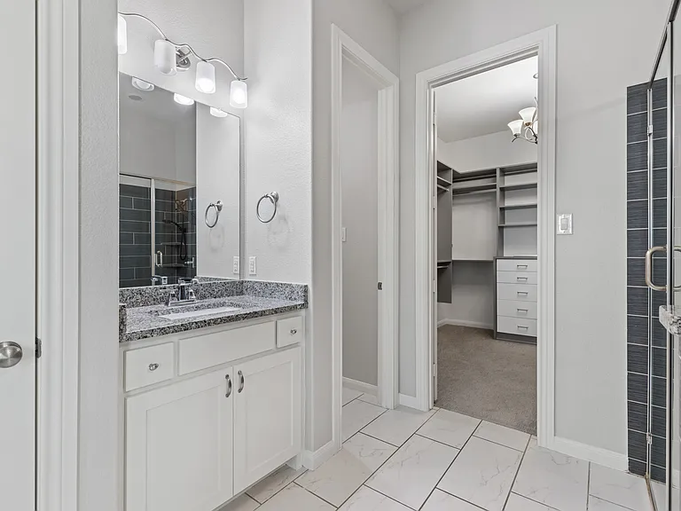 Spa-inspired ensuite bath featuring dual granite vanities, a framed walk-in shower with bench seating and custom walk in closet