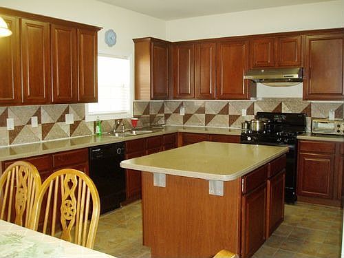 Kitchen has cherry cabinet, corrian countertop, tile floor.