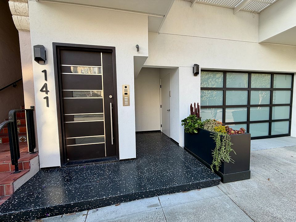 Close up of front door to building, as well as garage door and side door to garage.