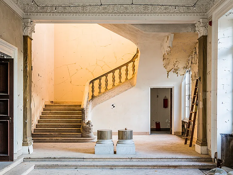Before: Ornate staircase lit from 2nd level during the renovation