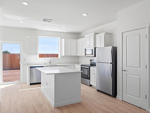 The kitchen has stainless steel appliances and plank flooring.