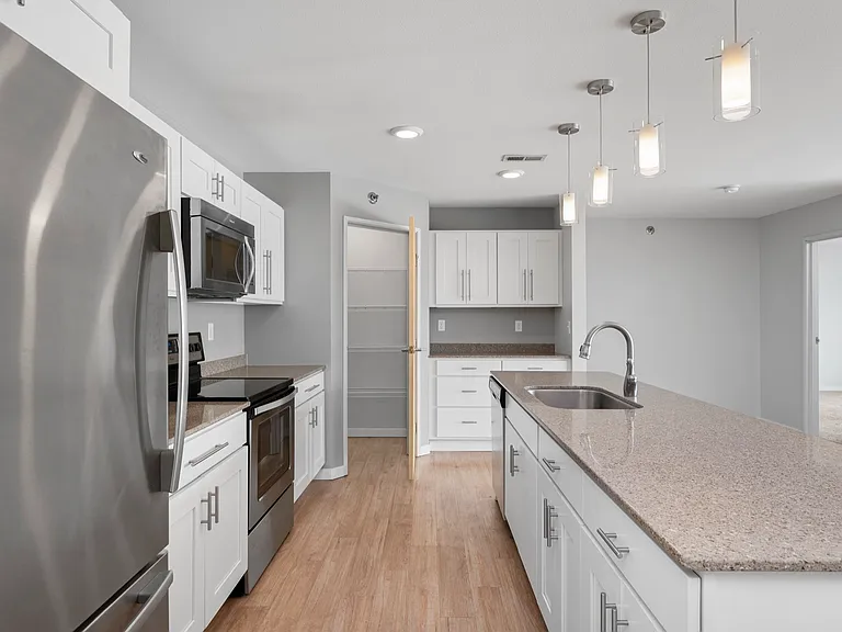 Modern kitchen with sleek stainless steel appliances, elegant pendant lighting, and spacious granite countertops. Modern kitchen with sleek stainless steel appliances, elegant pendant lighting, and spacious granite countertops.