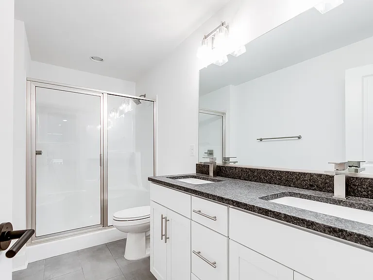 Primary bath with tile floors, walk-in shower with glass door, and double vanity