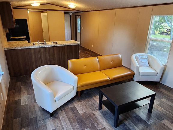 Partially furnished living room includes a futon, two chairs, and a coffee table.