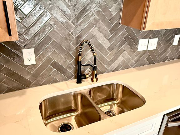 Chevron style backsplash with black and gold kitchen faucet