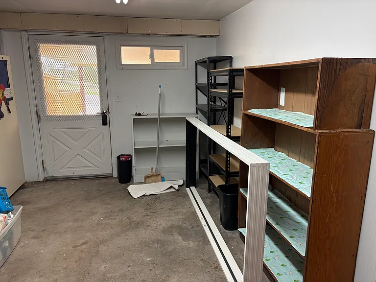 Basement storage shelving and door to Carport