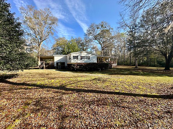 View from the front showing both the front and side porches that overlook large grass lawns.