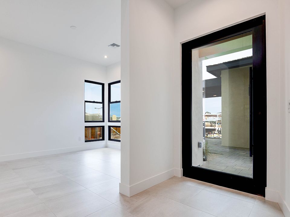 A spacious, minimalist interior with a large black-framed mirror reflecting the view through the win