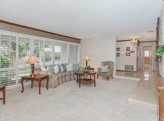 Living room as you enter the home with plantation shudders and double-sided fireplace