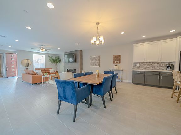 A stylish dining room with a large table surrounded by blue chairs, perfect for gatherings. The open layout connects to the kitchen, creating a seamless flow.