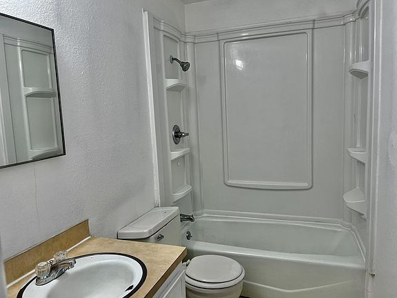 newer tub surround freshly caulked. Vanity freshly caulked and painted.