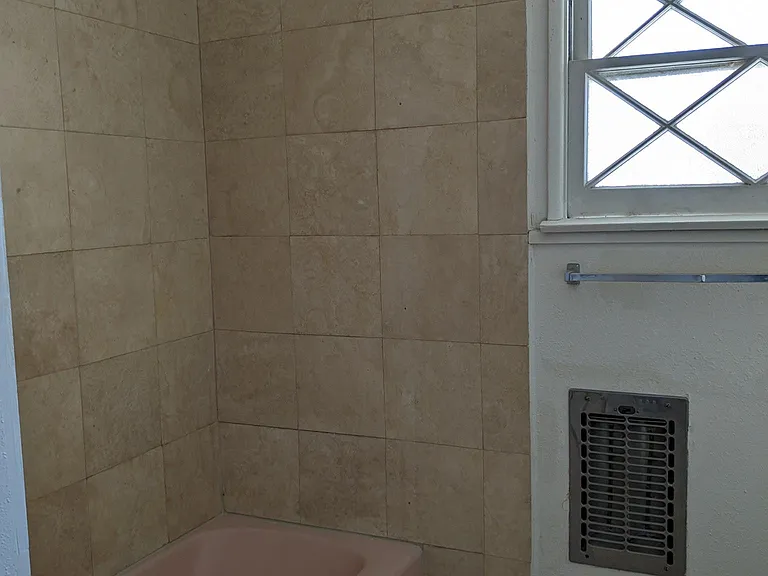 bathroom off hallway travertine stone showing shower and floors