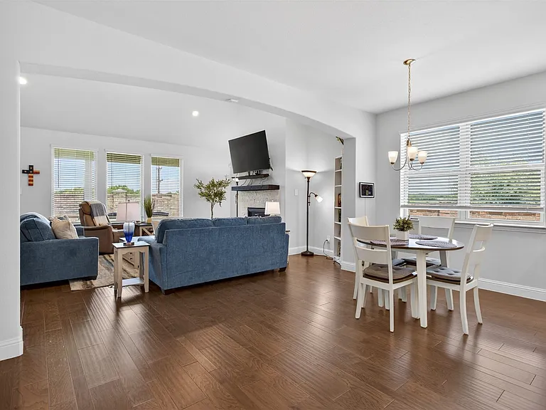 Open-concept living area with wood-finish flooring, recessed lighting, and a prominent fireplace with a stone surround